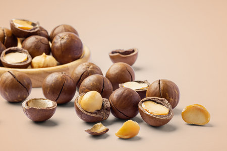 Macadamia nuts with cracked nut and shell on light brown background, closeupの写真素材
