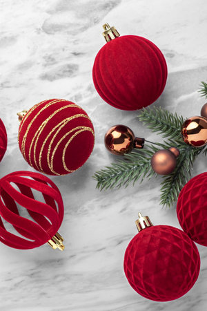Red velvet baubles, Christmas balls and pine branch ornaments on marble table, top viewの写真素材