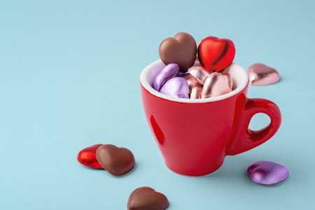 Valentines background, heart shaped chocolate in red cup on blue background, copy spaceの写真素材