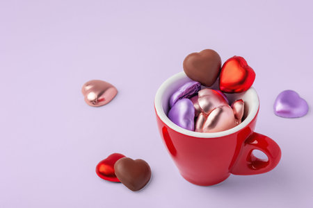 Valentines background, heart shaped chocolate in red cup on pastel purple background, copy spaceの写真素材