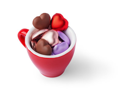 Sweet love concept, Red coffee cup filled with colorful heart shaped chocolates isolated on white background with copy spaceの写真素材