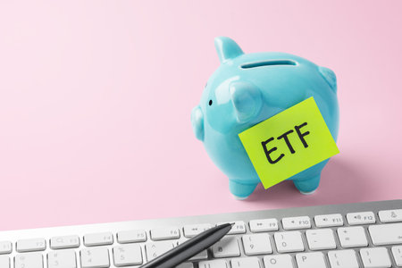 Financial planning and savings for ETF investment. Piggy bank and computer keyboard on pink...