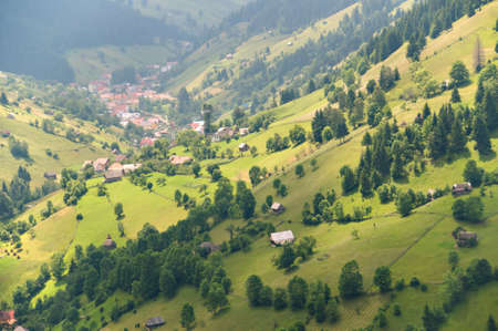 Aerial view of village between beautiful green fields on hillsの写真素材