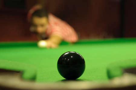 Close-up of snooker black ball next to a pocket, waiting to be potted by player in the backgroundの写真素材