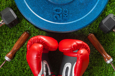 Dumbbells, skipping rope, boxing gloves and weight on green artificial grassの写真素材