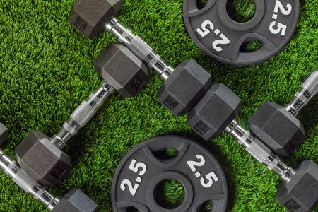 Dumbbells and weights on the grass close up backgroundの写真素材