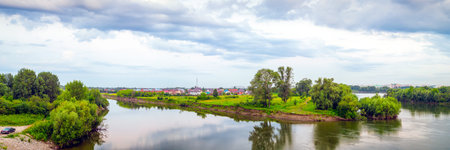 Landscape of a green forest and a small river with a mirror image of trees on a summer day, a blue...