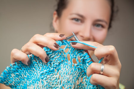 A young dark-haired married woman smiling and pointing at the camera as knit from natural woolen...