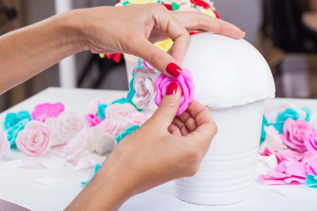 Close-up of a young woman doing her own hands glues the petals  on an artificial rose from...