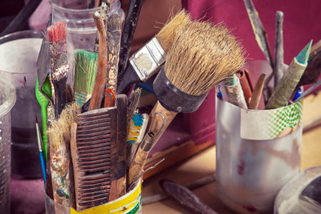 On the table in the glass are a lot of artist's brushes of different sizes, pencils and other...