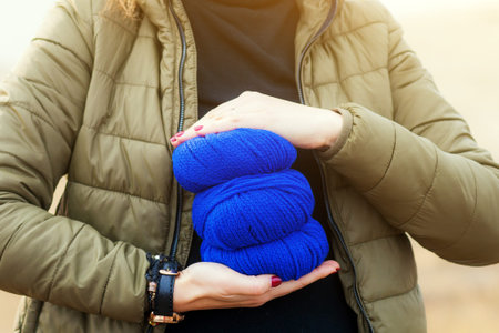 A close-up of a woman in a black sweater, a green jacket with bright red nails holding in her hands...