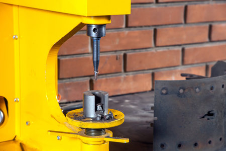 A close-up of yellow riveter machine for riveting brake pads  in the workshop in the background a brick wallの写真素材