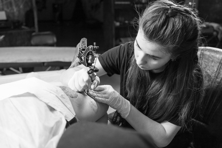 Beautiful dark-haired woman tattoo artist drawing a tattoo for a tattoo, close-up, bottom viewの写真素材