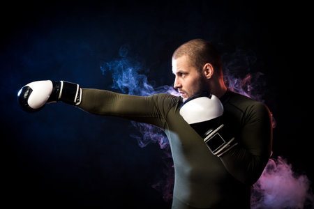 A strong dark-haired sportman  in a green sports shirt and black and white gloves  does an uppercut ...