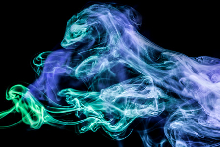 Dense multicolored smoke of   blue  colors on a black isolated background. Background of smoke vapeの写真素材