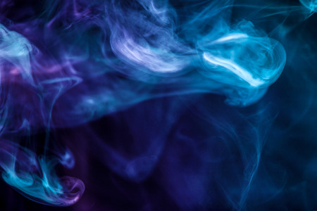 Dense multicolored smoke of   blue colors on a black isolated background. Background of smoke vapeの写真素材