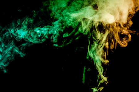 Thick yellow and green colorful smoke of on a black isolated background. Background from the smoke of vapeの写真素材