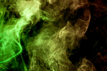Thick colorful smoke of  yellow and  green on a black isolated background. Background from the smoke of vapeの写真素材