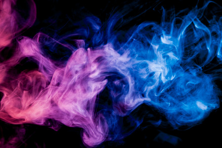 Dense multicolored smoke of   blue, and pink colors on a black isolated background. Background of smoke vapeの写真素材