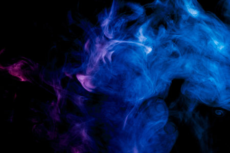 Thick colorful smoke of blue and pink  on a black isolated background. Background from the smoke of vapeの写真素材