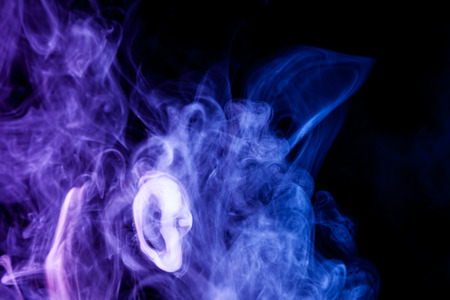Multi-colored smoke with clubs of blue and purple on a black isolated backgroundの写真素材