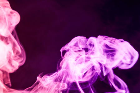 Dense pinkmulticolored smoke on a black isolated background. Background of smoke vapeの写真素材