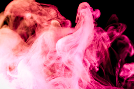 Dense  pink and red multicolored smoke on a black isolated background. Background of smoke vapeの写真素材