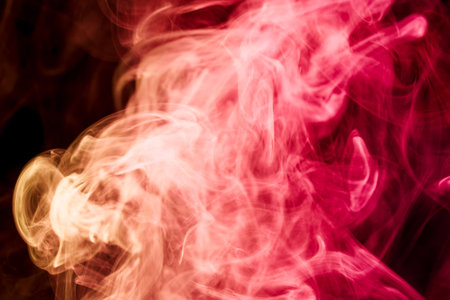 Colorful  red and pink smoke  on a black isolated background. Background from the smoke of vapeの写真素材