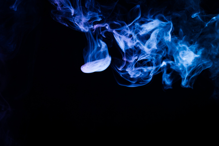 Thick blue colorful smoke on a black isolated background. Background from the smoke of vapeの写真素材