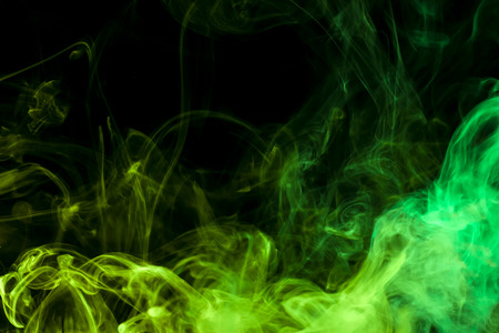 Thick colorful smoke of green and blue on a black isolated background. Background from the smoke of vapeの写真素材