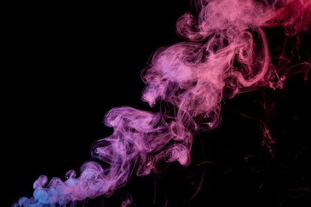 Thick colorful smoke of purple, blue and pink on a black isolated background. Background from the smoke of vapeの写真素材
