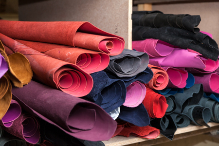 Close-up of even rows of natural leather of pink, red, gray and black shoes and jacketsの写真素材