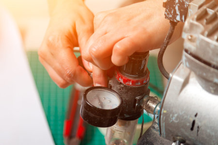 Close-up of a woman working adjusts the sensor on a metallic gray airbrushの写真素材
