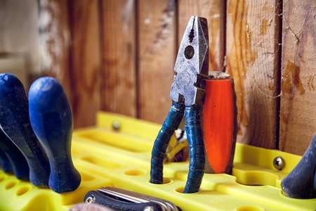 A close-up of a set of tools: pliers, a screwdriver, a wrench on a yellow standの写真素材