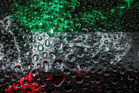 Close-up of a drop of water against a background of the national flag of  Kuwait on an isolated...