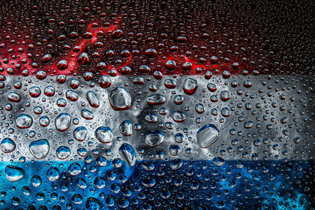 Close-up of a drop of water against a background of the national flag of  Luxembourg on an isolated backgroundの写真素材