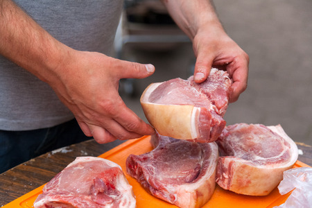 Close-up of a cook man is spreading sauce and salt large pieces of fresh pork entrecote for grilling. The man is cooking shish kebabの写真素材