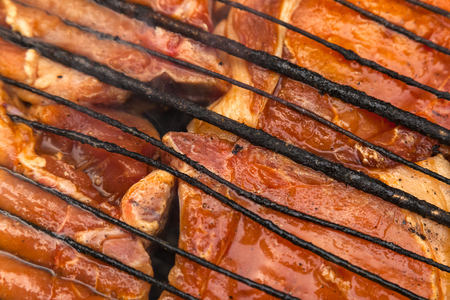A close-up of the pies of entrecote pork in teriyaki sauce is fried in a grill. Preparation of a shish kebab on a summer day at the cottageの写真素材