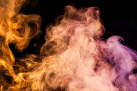 Thick colorful smoke of pink, orange  on a black isolated background. Background from the smoke of vapeの写真素材
