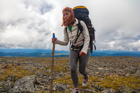 Atmospheric moment in mountains. Hiking woman with backpack traveler on top of mountains. Stylish woman hiking, in the background a green forest, field and high mountainsの写真素材