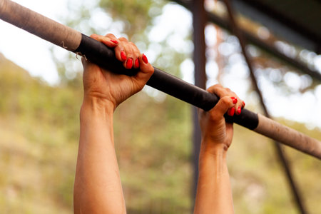Close-up Young woman hanging on the crossbar for pull-ups, hands in magnesia against the backdrop of...