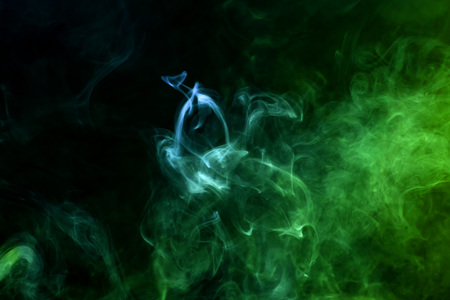 Cloud of blue and green smoke on a black isolated background. Background from the smoke of vapeの写真素材