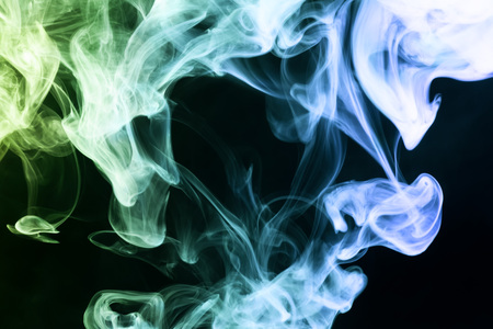 Thick colorful blue and green  smoke  on a black isolated background. Background from the smoke of vapeの写真素材