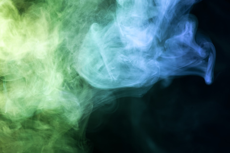 Colorful green and blue smoke  on a black isolated background. Background from the smoke of vapeの写真素材