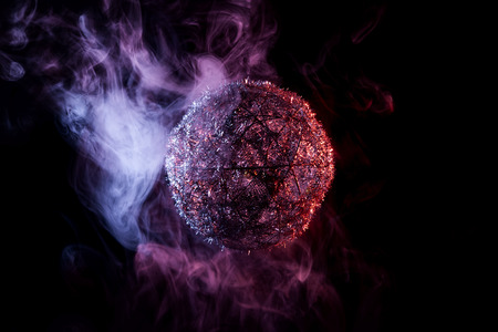 Silver shiny decoration Christmas balls in colored purple-red smoke, on an isolated black background. Concept of a modern Christmas card. Disco-ball in colored smoke in the darkの写真素材