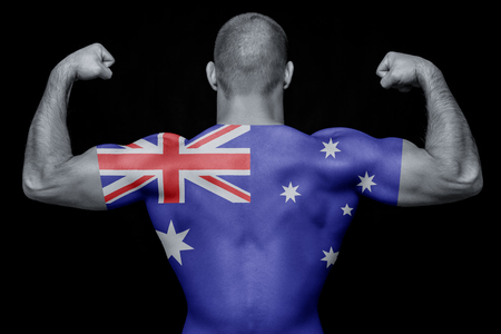 The back of a young athletic man wearing a T-shirt with the national flag of Australia on a black isolated background. The concept of national pride and patriotismの写真素材