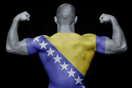 The back of a young sports man wearing a T-shirt with the national flag of Bosnia Herzegovina on a black isolated background. The concept of national pride and patriotismの写真素材