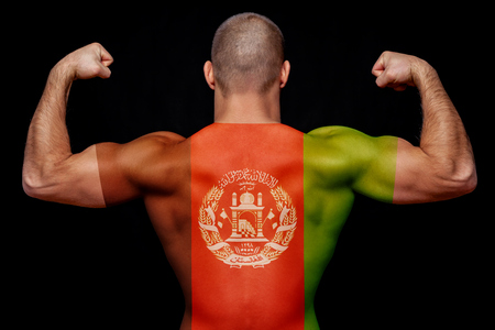 The back of a young athletic man wearing a T-shirt with the national flag of Afghanistan on a black isolated background. The concept of national pride and patriotismの写真素材