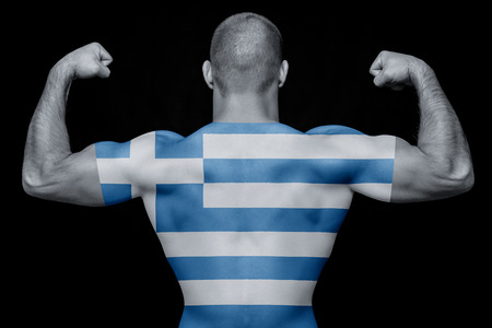 The back of a young sports man wearing a T-shirt with the national flag of Greece on a black isolated background. Concept of national pride and patriotismの写真素材