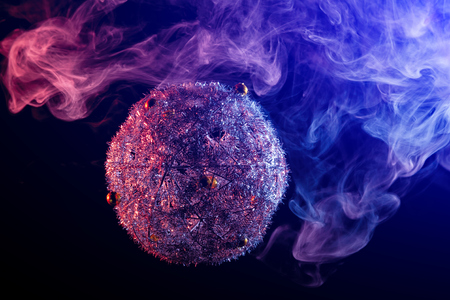Close up  of a  silver shiny decoration Christmas balls in colored purple-blue smoke, on an isolated black background. Concept of a modern Christmas card. Happy new year disco-ball in colored smokeの写真素材